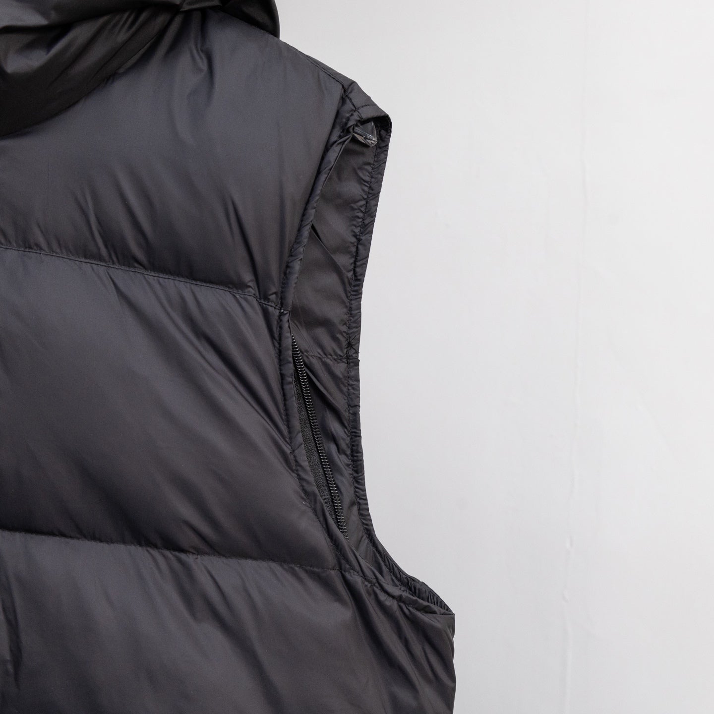 Black sleeveless puffer vest with side seam paneling and zipper trim