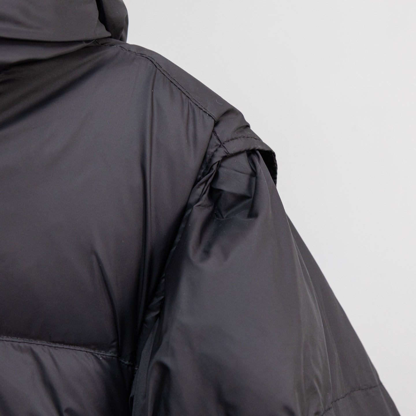 Black puffer jacket side view with seam stitching and smooth outer fabric