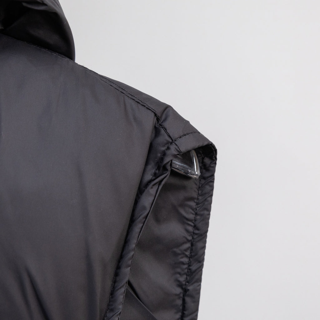 Black quilted puffer vest with hood, stitched shoulder panel, and visible cuff seam