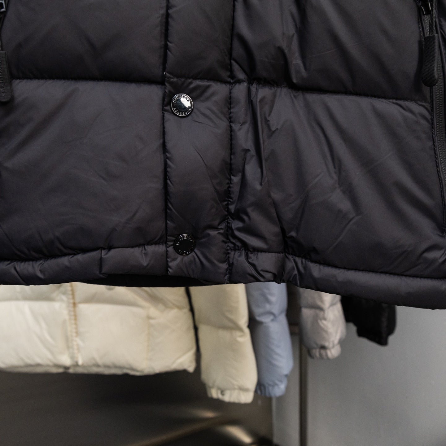 Black puffer vest front with button closures and quilted horizontal baffle lines