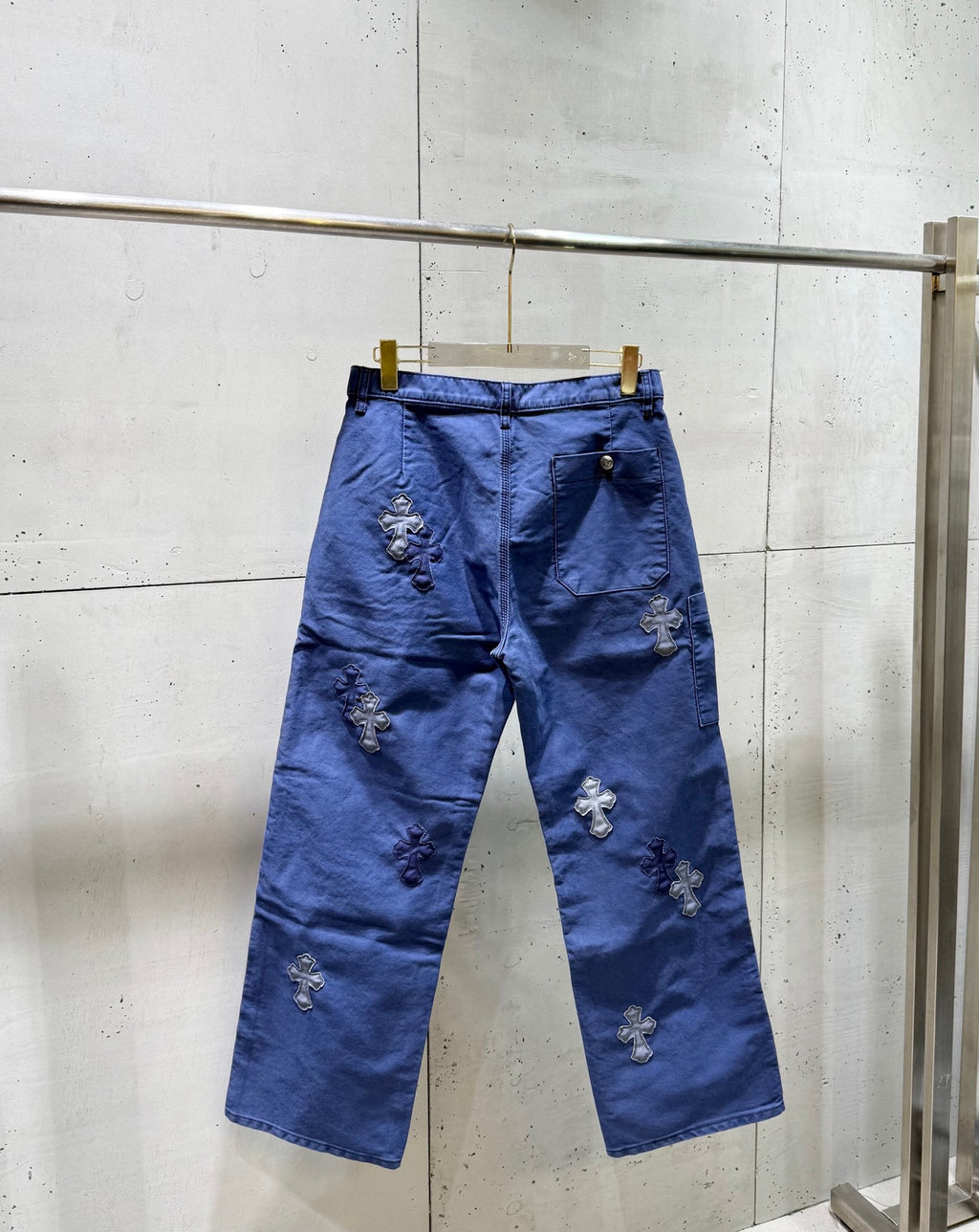Blue pants with cross appliques across the back and button closure