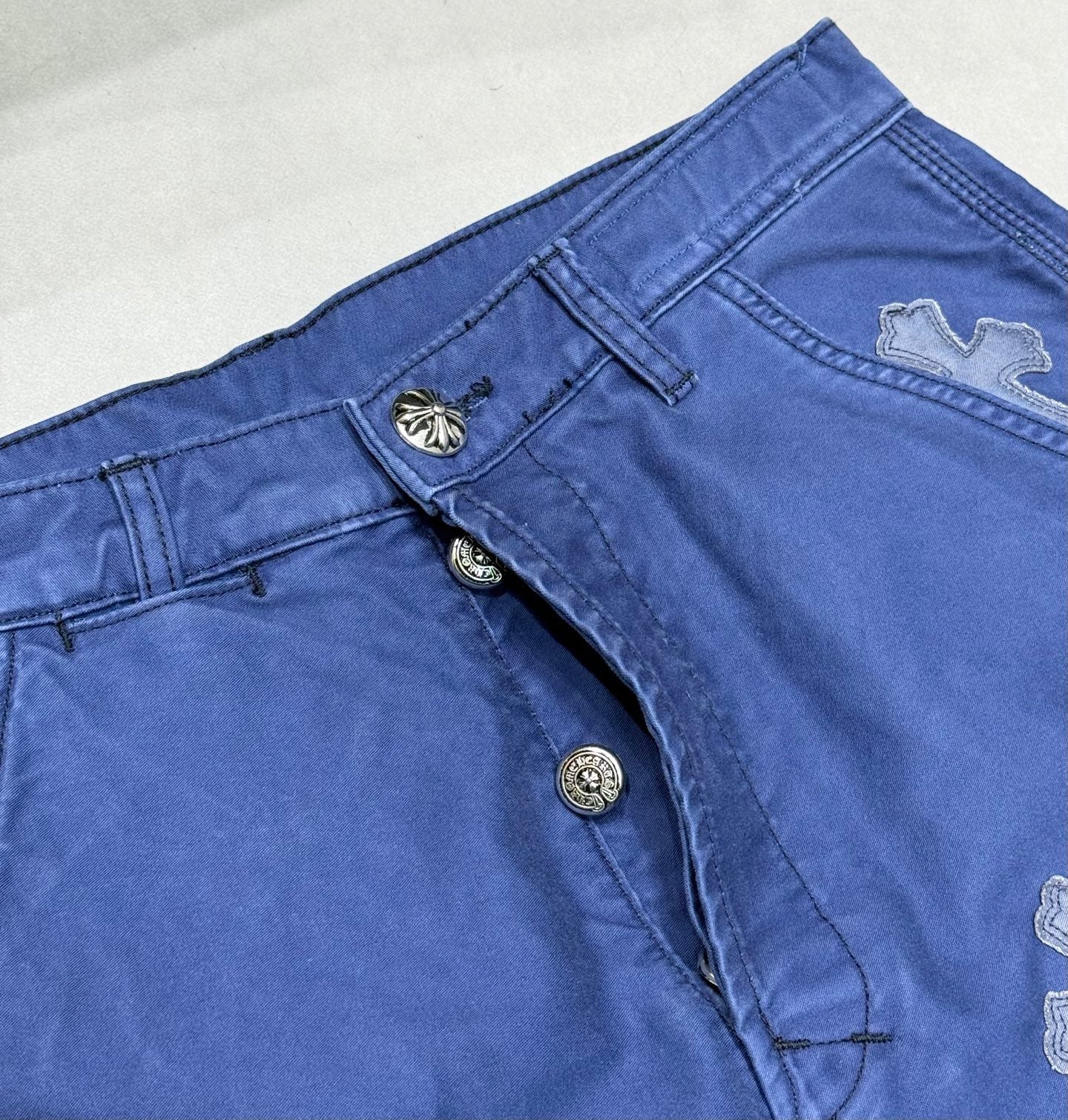 Blue pants front with snap buttons and cross applique detail