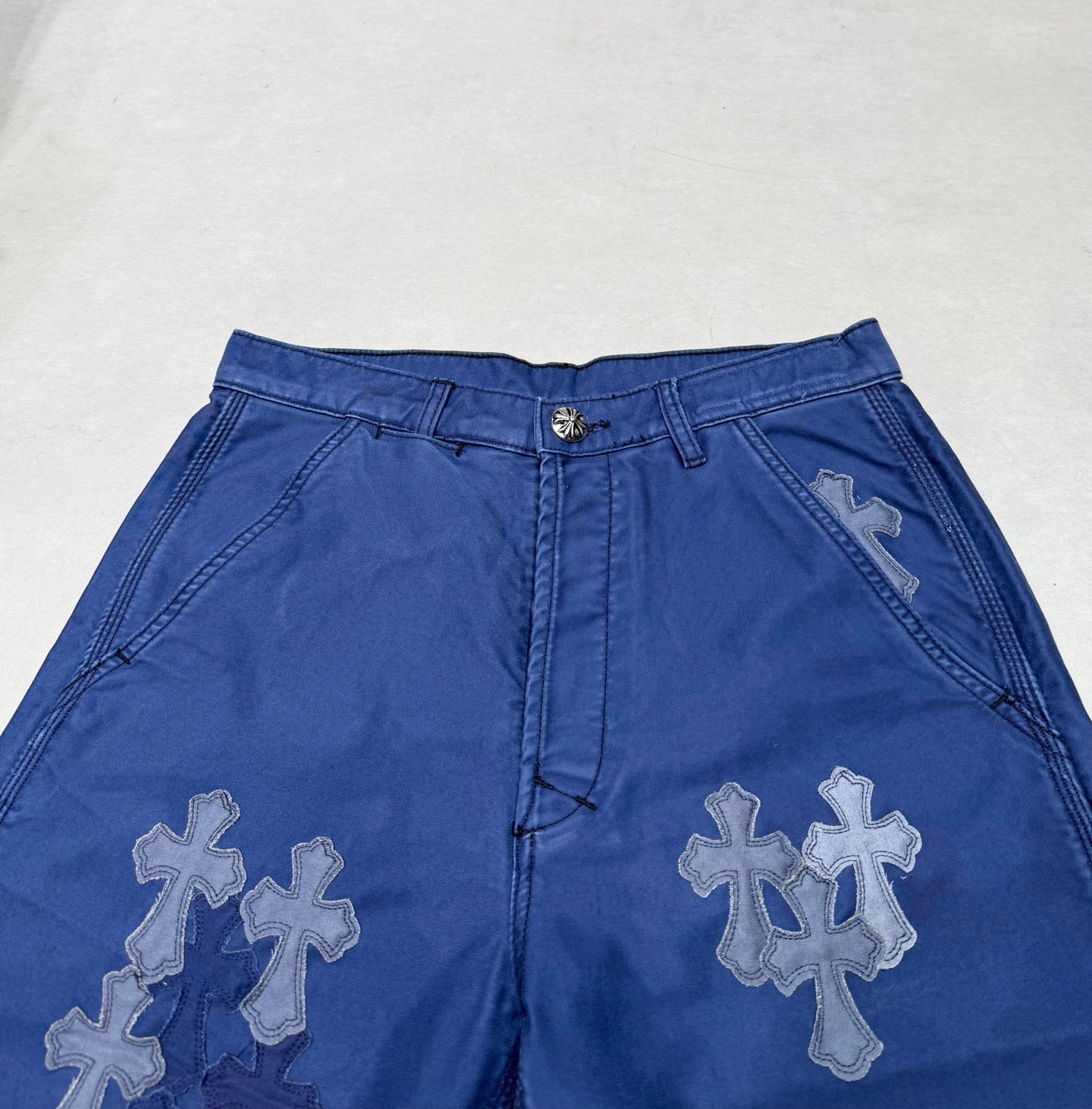 Blue pants waistband with belt loops and large cross appliques on front