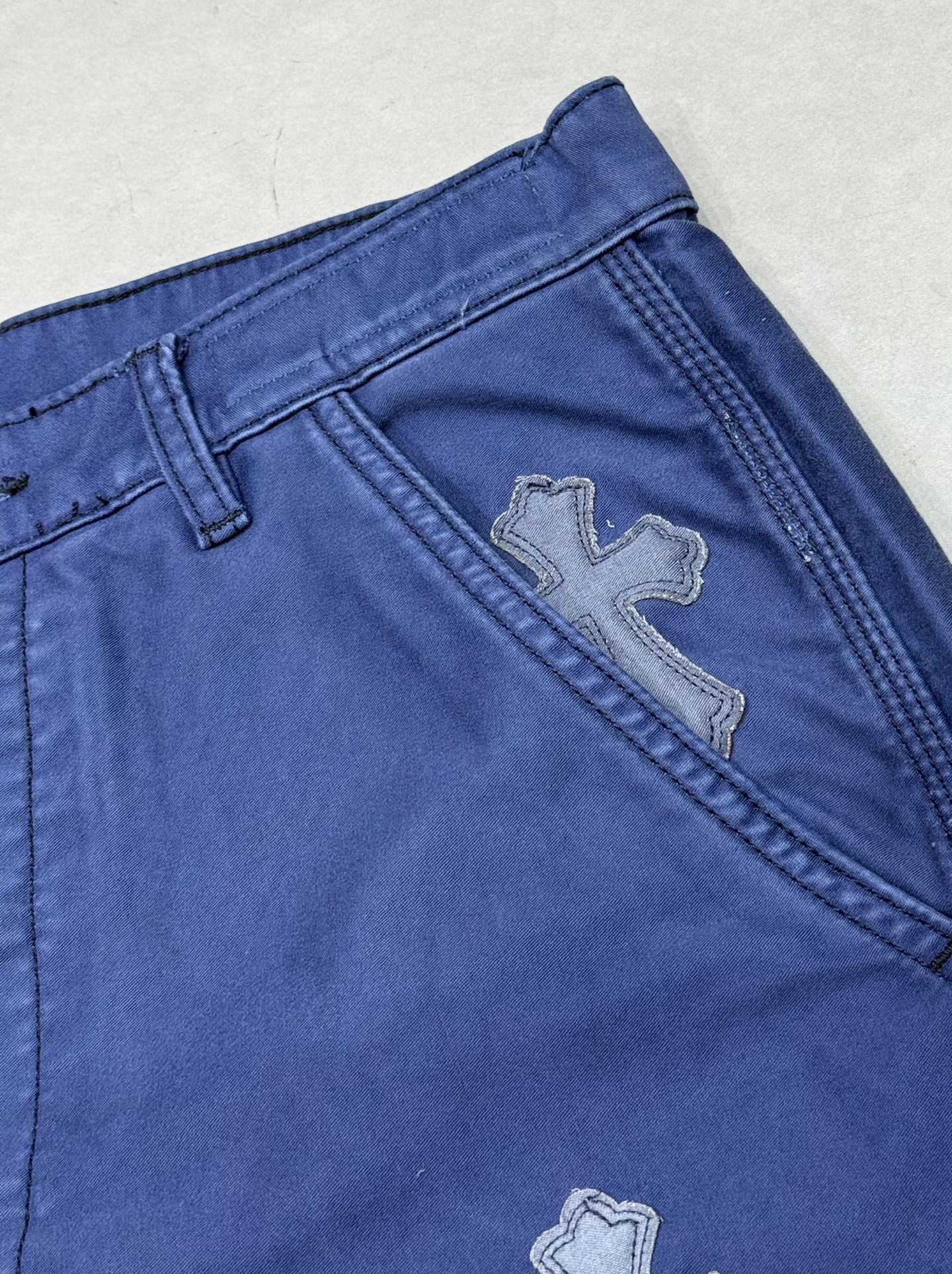 Blue pants with embroidered cross patch near side seam
