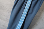 Blue pants with contrast side stripe trim along the leg