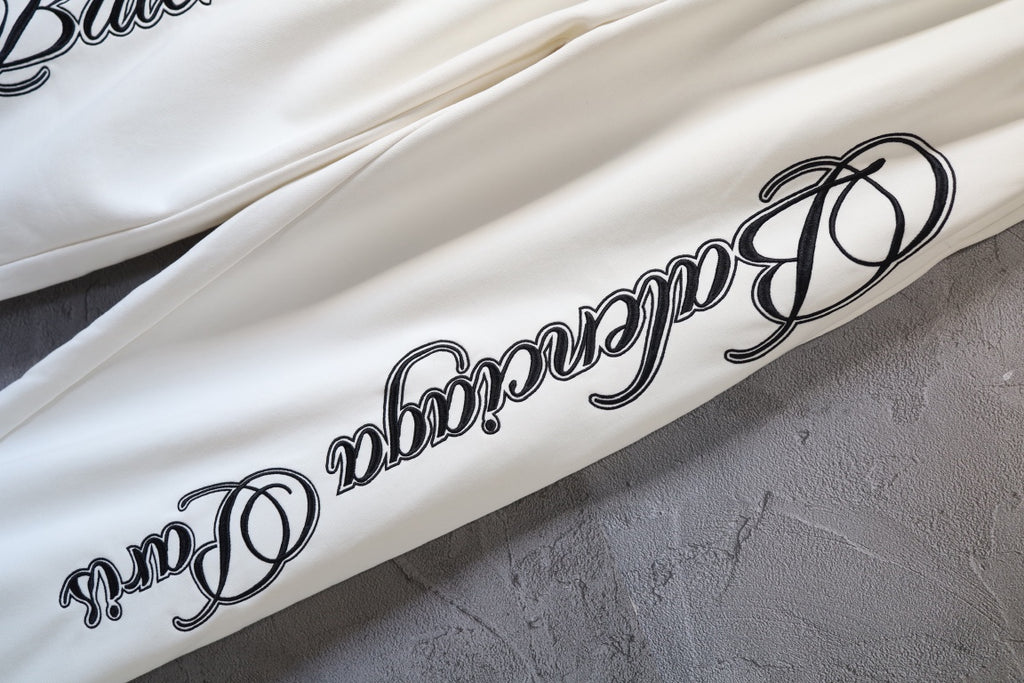 White Balenciaga pants with black script logo print along the leg