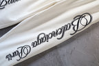 White pants with black curved logo text along the side