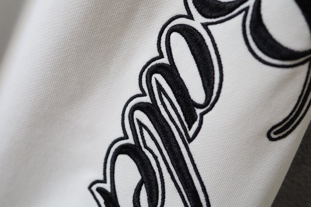 White fabric pants with black script logo graphic on the leg