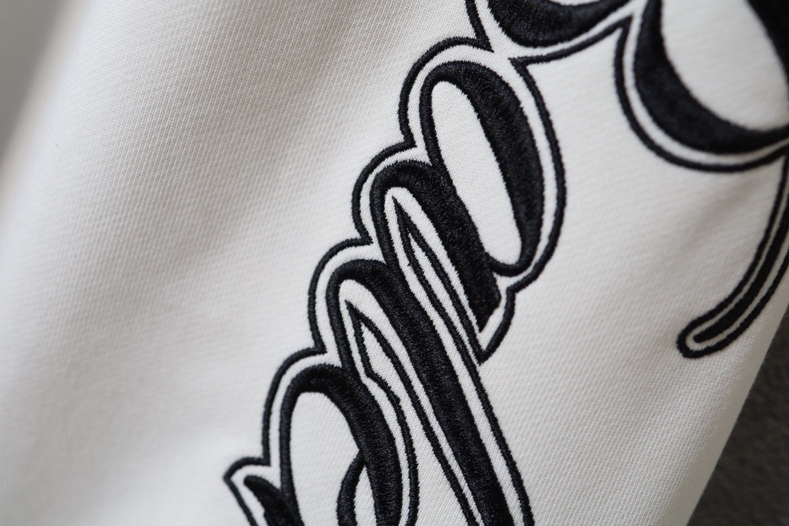 White fabric pants with black script logo graphic on the leg