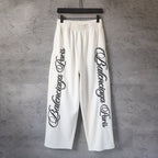 White wide-leg pants with elastic waistband and black logo print