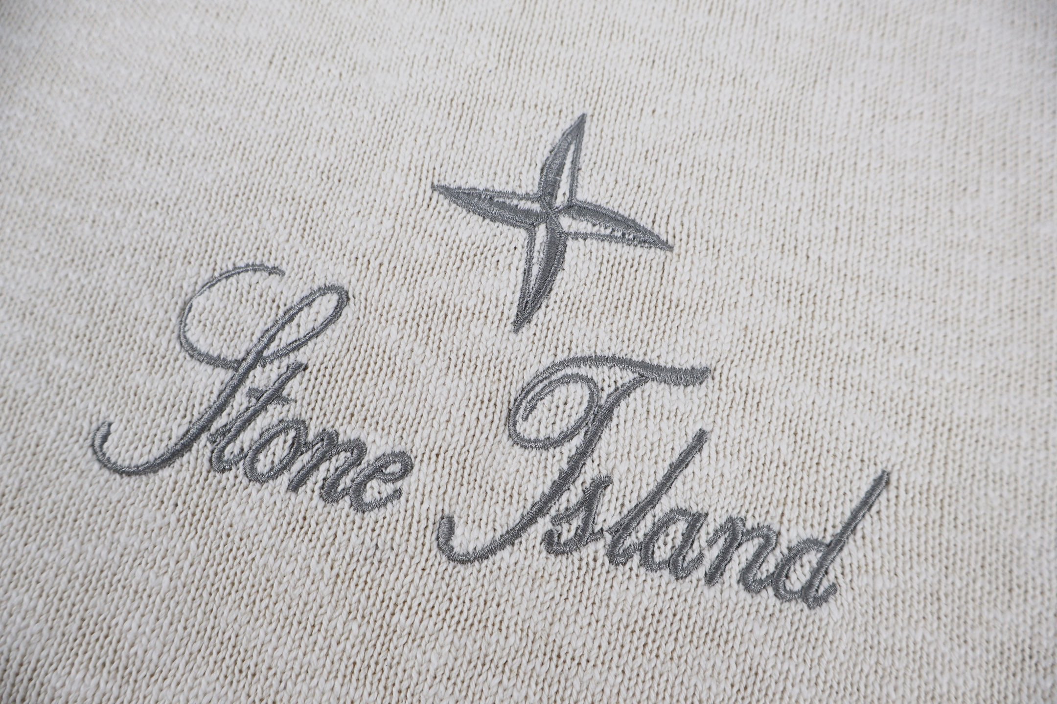 Stone Island logo on light beige knit sweater, star and script text