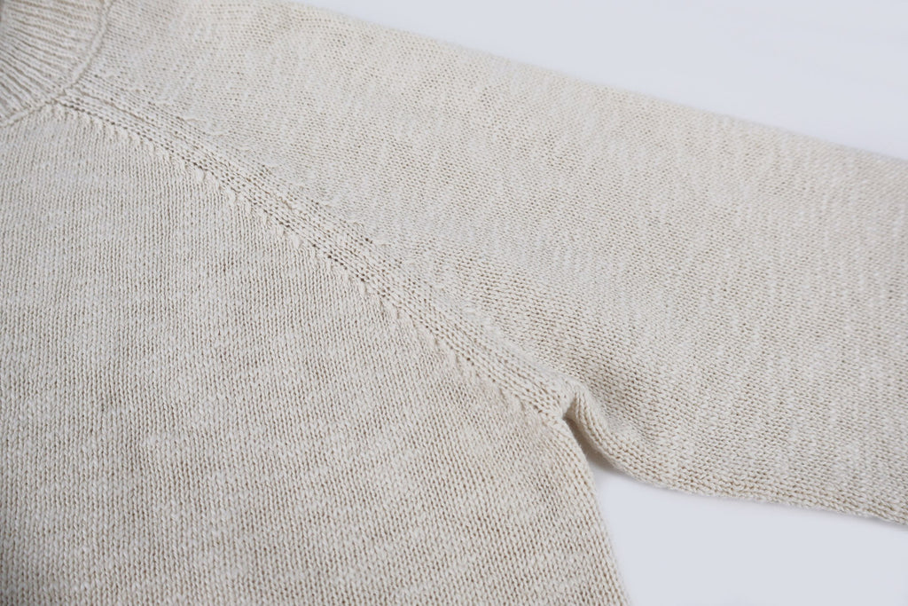 Light beige knit sweater sleeve and shoulder seam detail