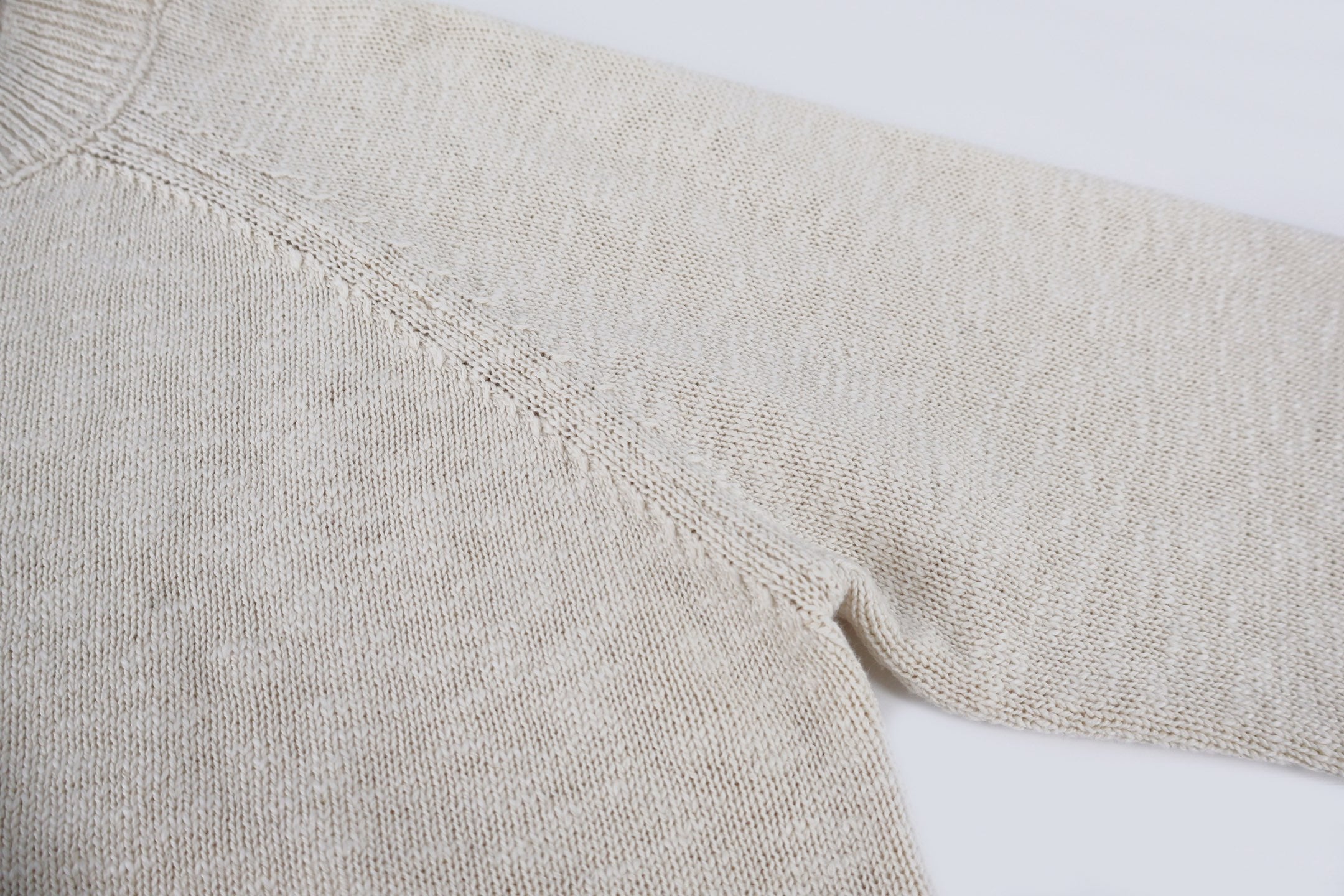 Light beige knit sweater sleeve and shoulder seam detail