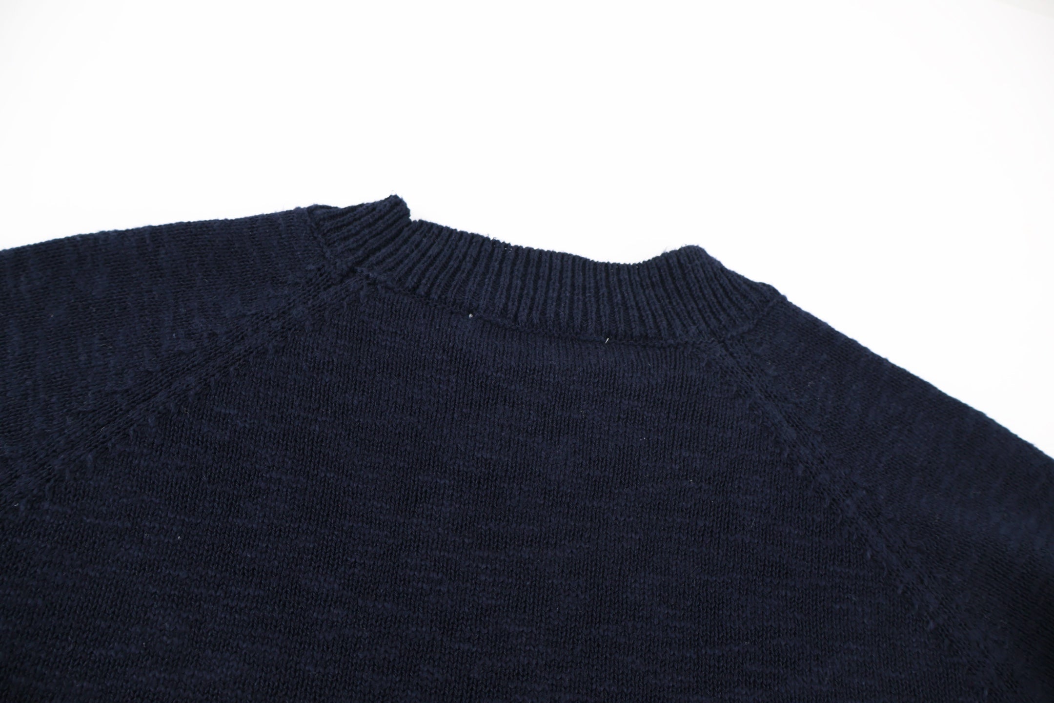 Dark navy knit sweater shoulder and upper back with ribbed crew collar