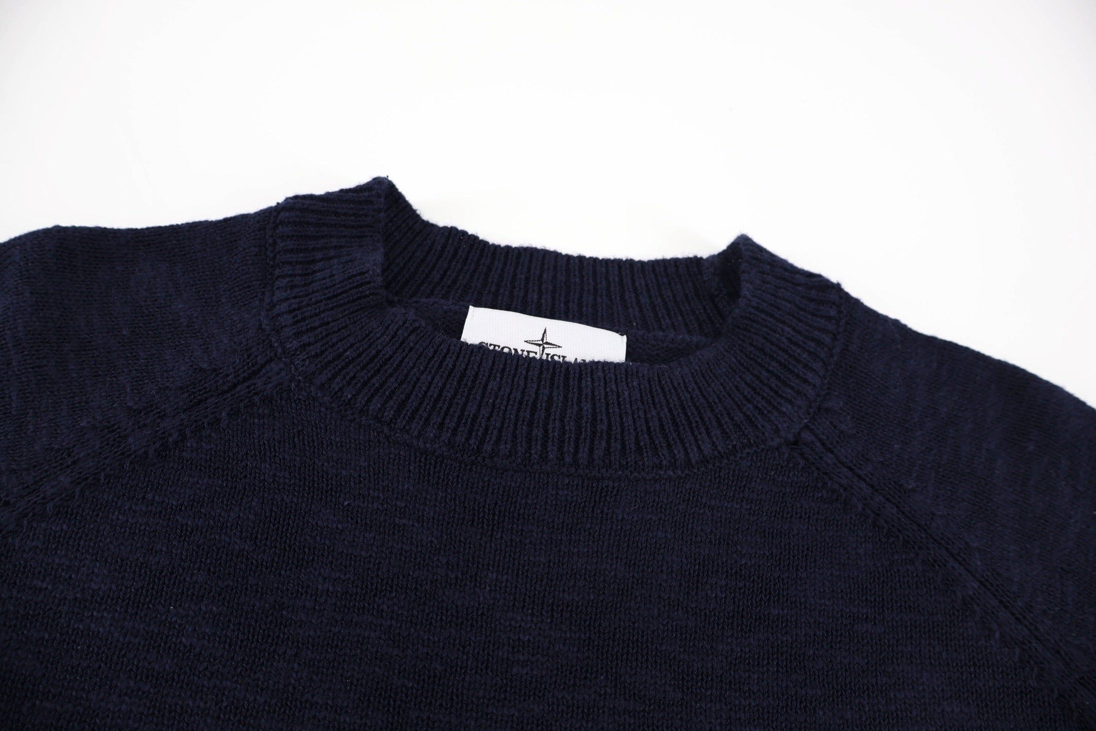 Dark navy crewneck sweater with ribbed collar and small interior brand label