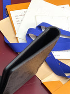 Small leather card holder wallet, close-up of edge with blue ribbon, dark blue-gray