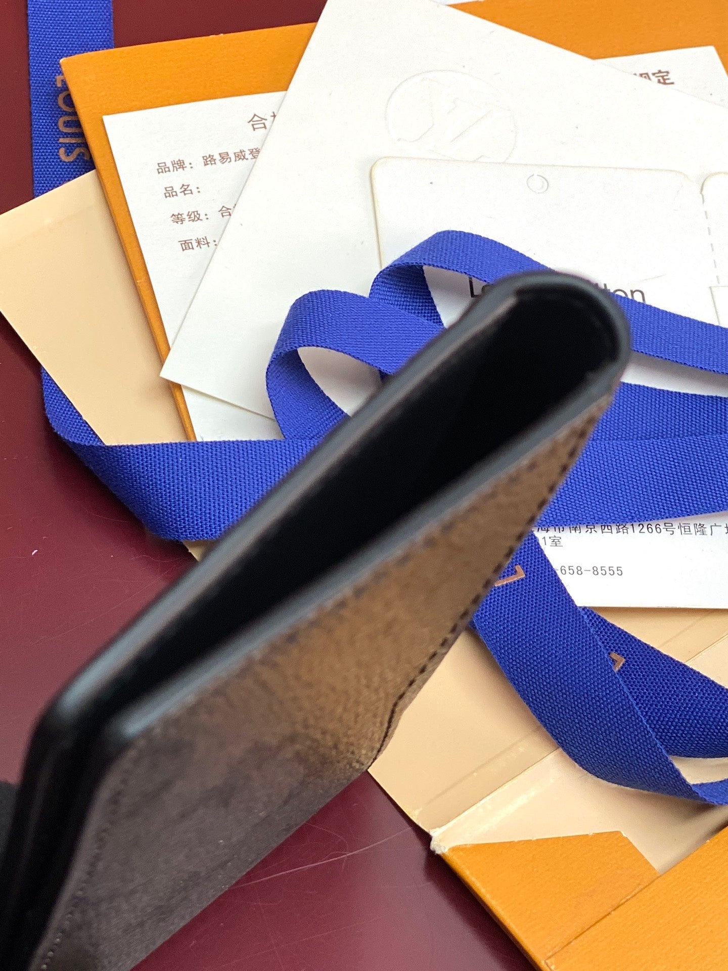 Small leather card holder wallet, close-up of edge with blue ribbon, dark blue-gray
