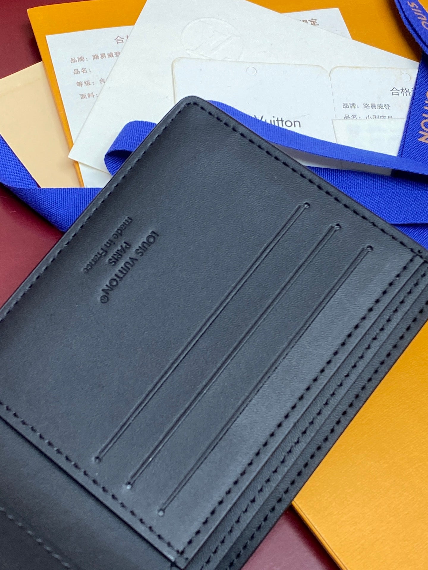 Blue leather wallet front with embossed logo and three stitched slot lines