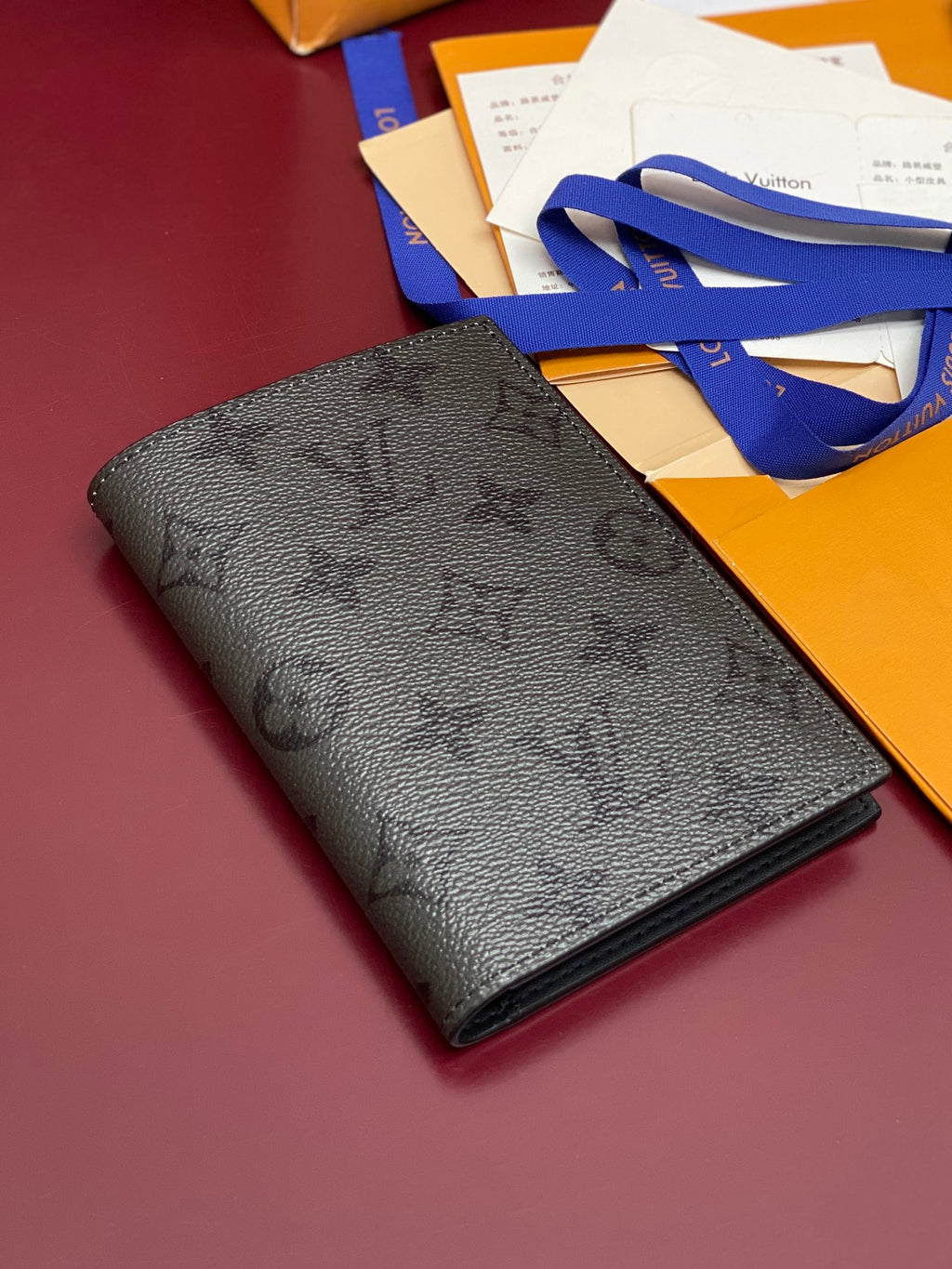 Black textured leather small bag lying flat with stitched trim and LV detail