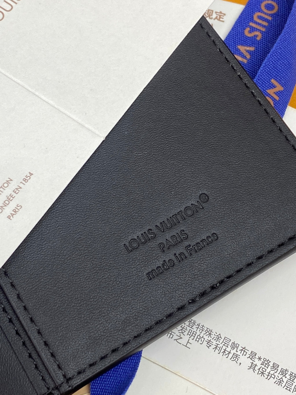 Small wallet bag close-up of dark logo patch and stitched border