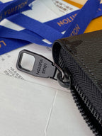 Small zip pouch close-up of black zipper pull with tag, textured leather