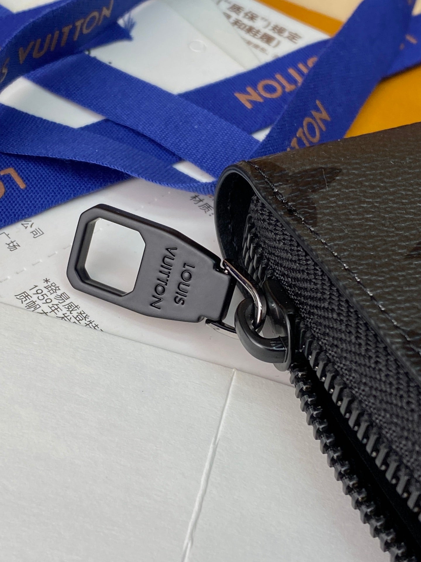 Small zip pouch close-up of black zipper pull with tag, textured leather