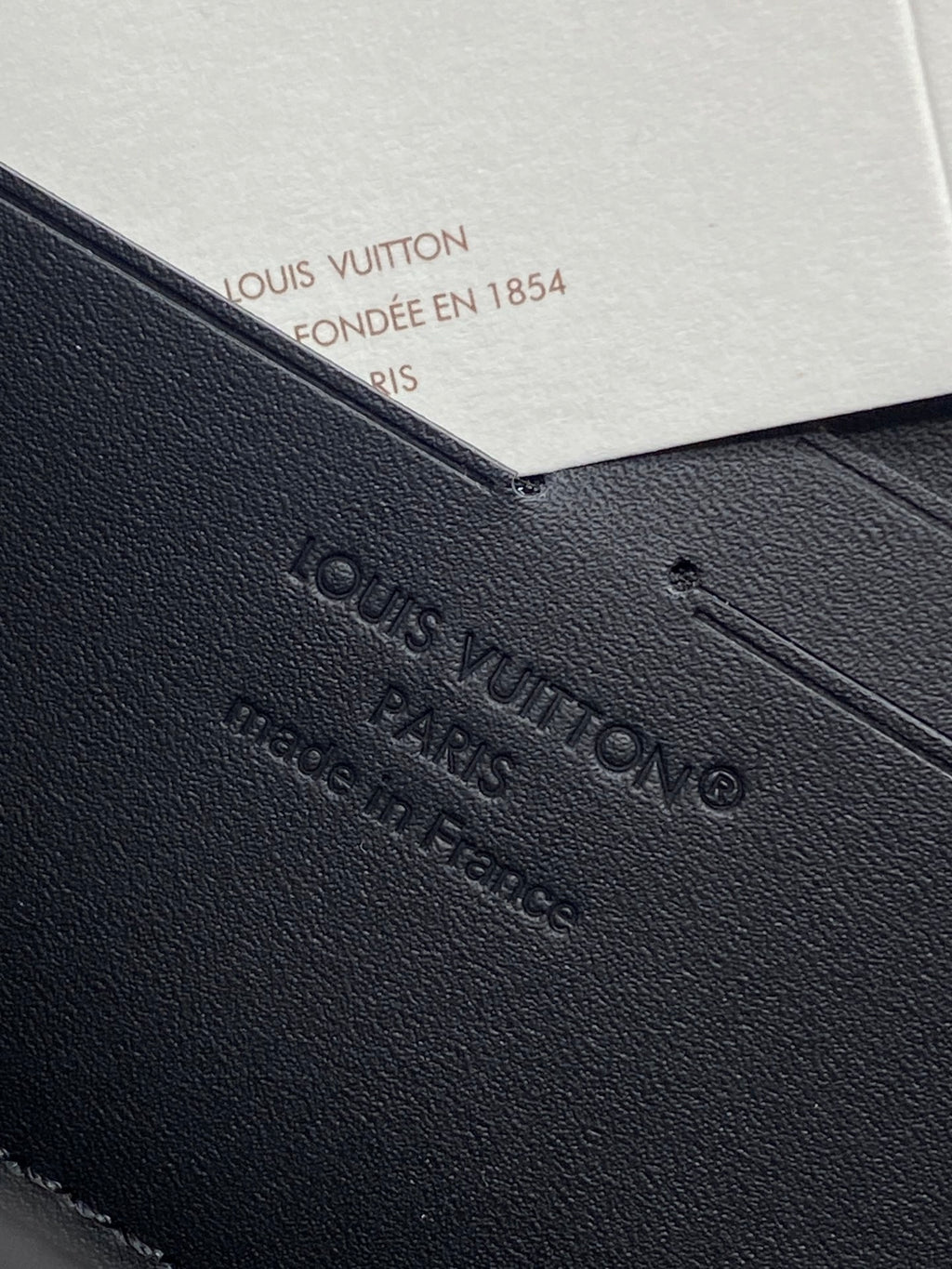 Small zip pouch detail with embossed Louis Vuitton logo on textured black leather