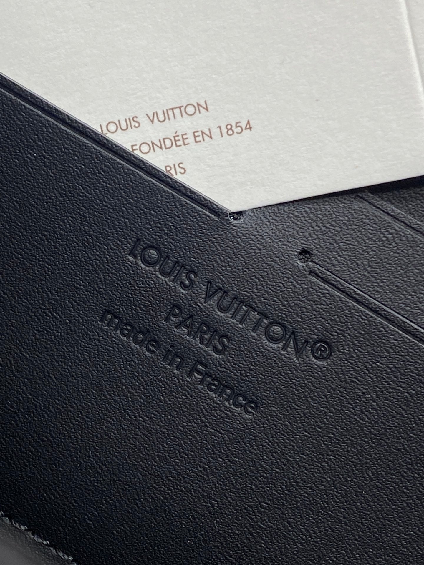 Small zip pouch detail with embossed Louis Vuitton logo on textured black leather