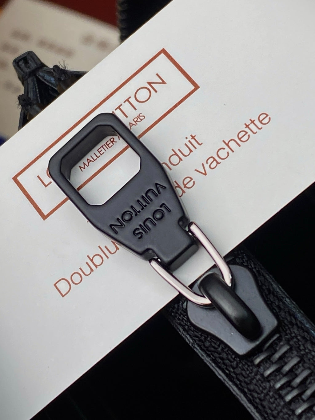 Small zip pouch close-up of black metal zipper pull and D-ring hardware