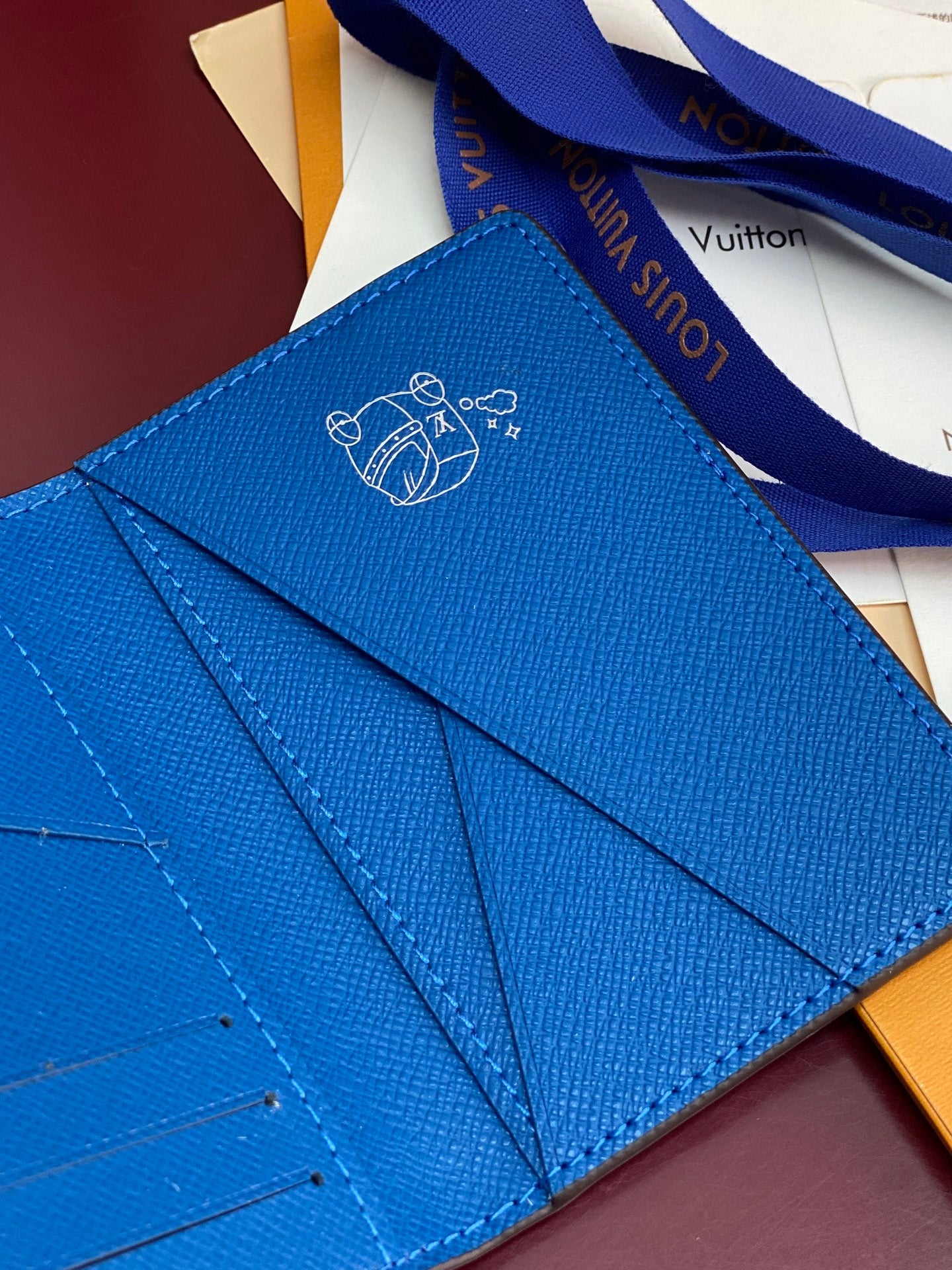 Small bag card holder interior view with blue leather and Louis Vuitton line artwork