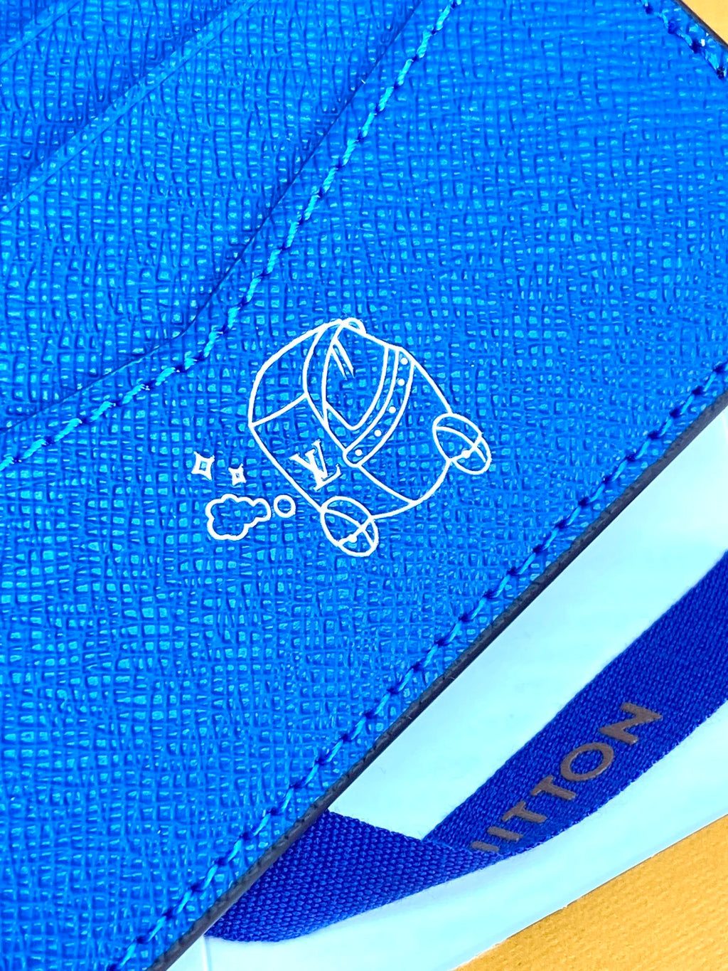 Blue small bag close-up of embossed logo on textured flap
