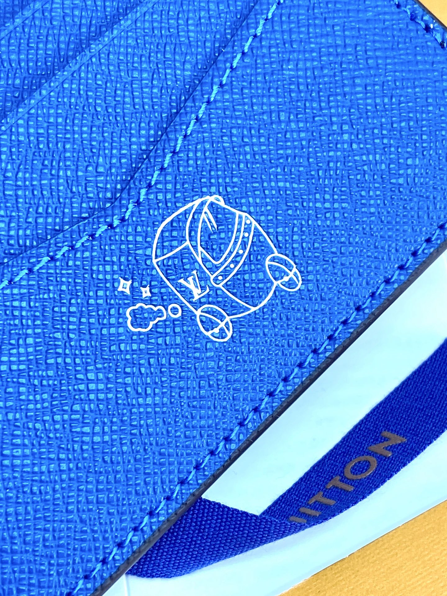 Blue small bag close-up of embossed logo on textured flap