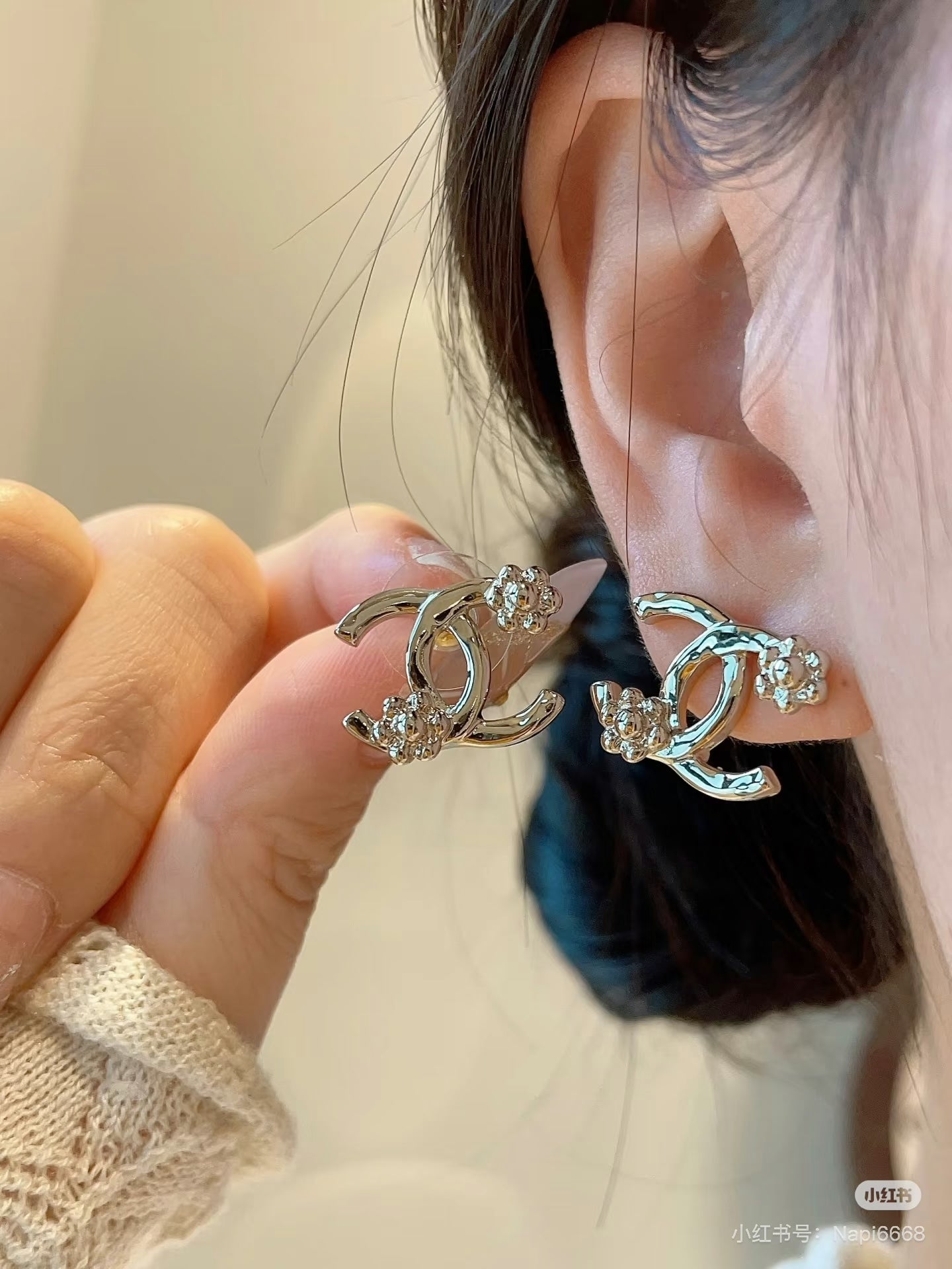 Chanel hoop earrings held in hand, gold-tone and crystal details