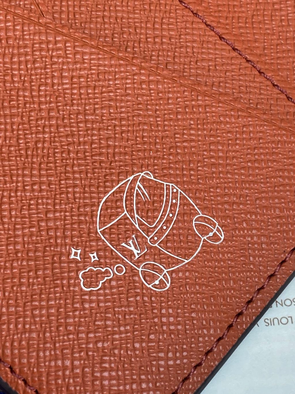 Louis Vuitton small wallet close-up of cartoon emblem on red leather surface