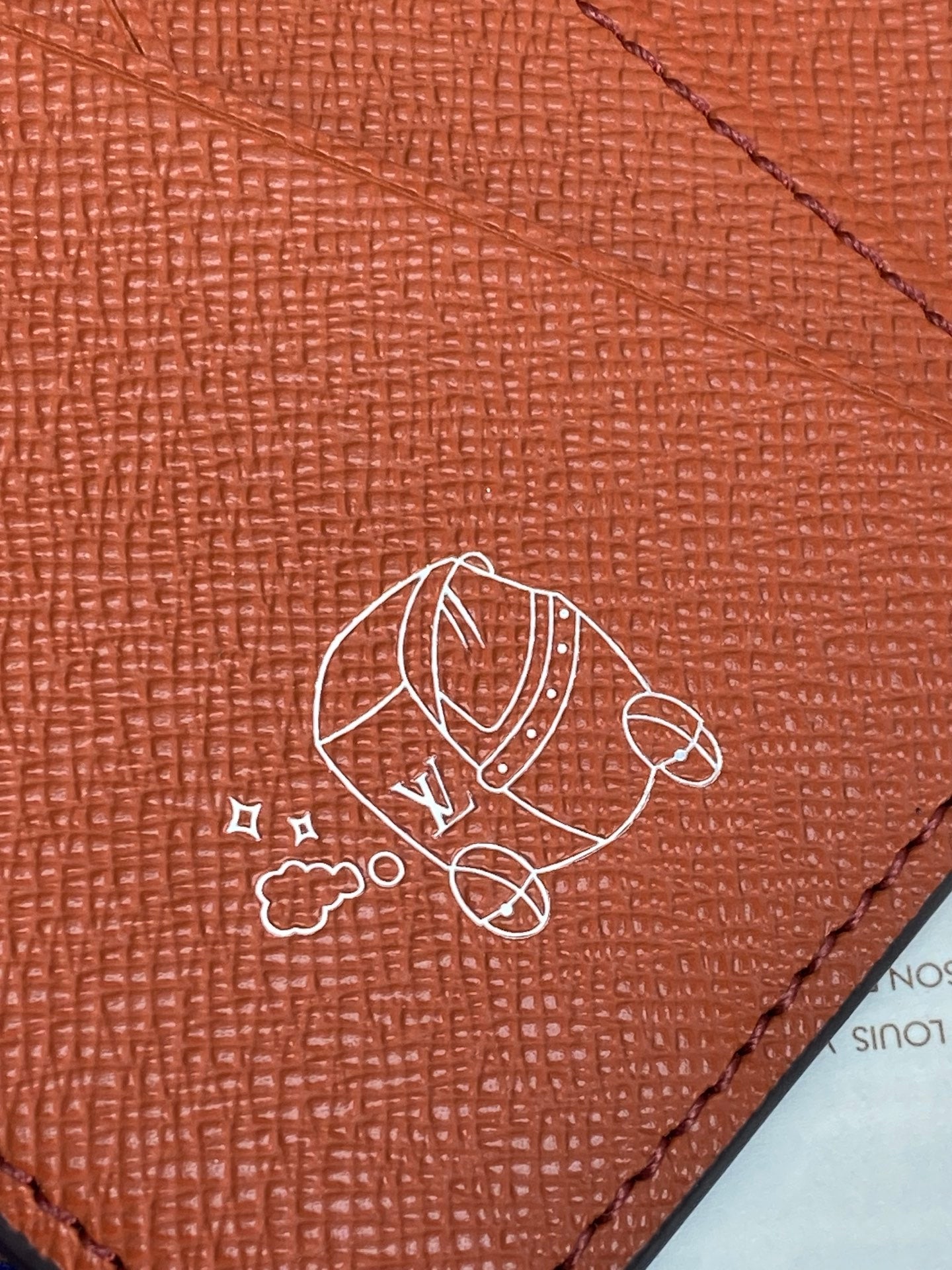 Louis Vuitton small wallet close-up of cartoon emblem on red leather surface