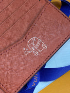 Small bi-fold card wallet close-up of embossed emblem on tan leather