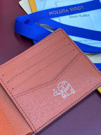 Small bi-fold card wallet close-up, tan leather with embossed crest