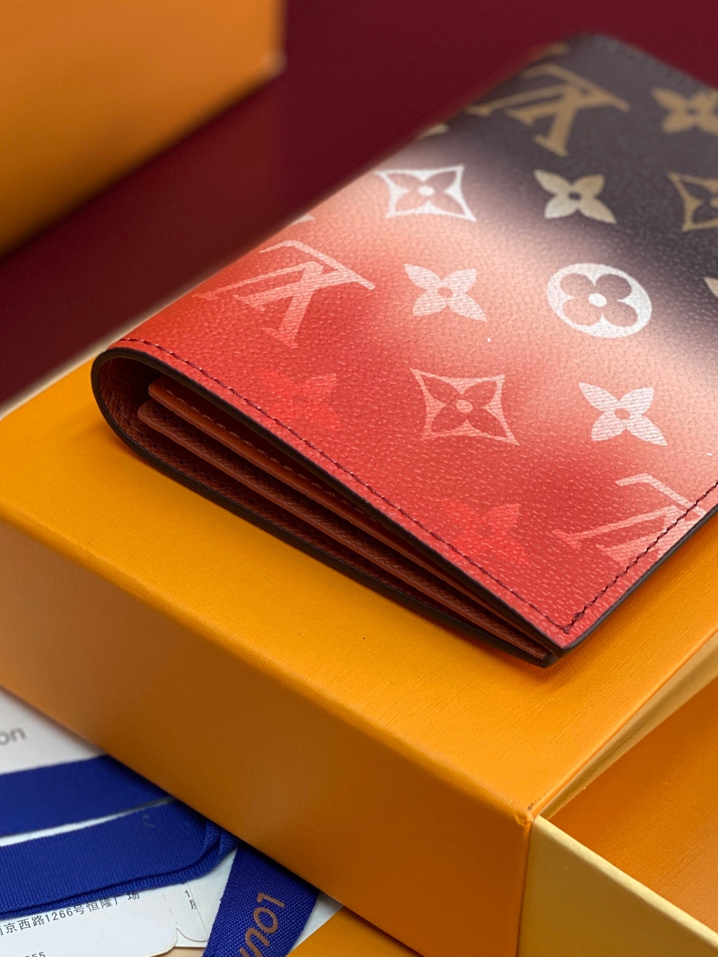 Small red card wallet with white monogram pattern, folded front and stitched edges