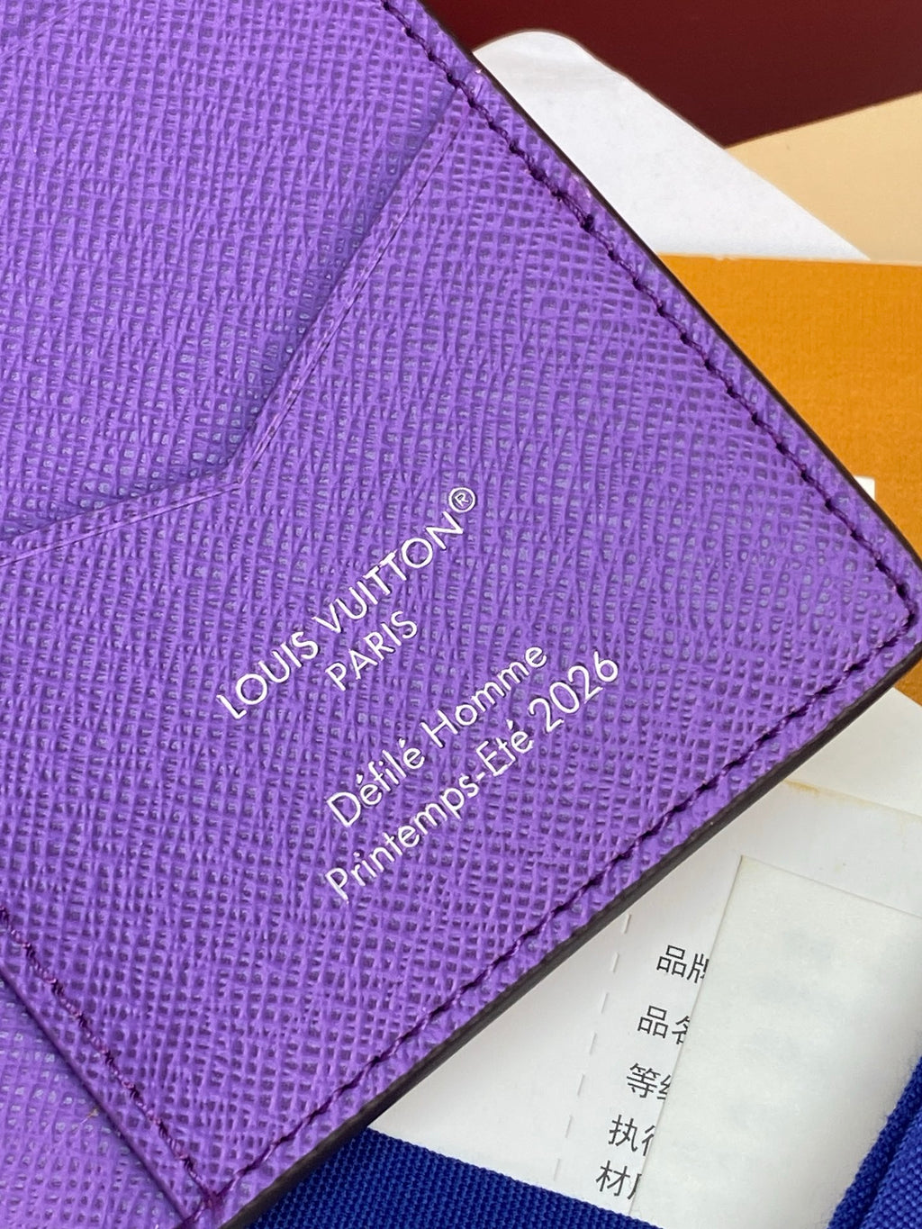 Small bag card holder close-up of purple logo stamp text on textured leather