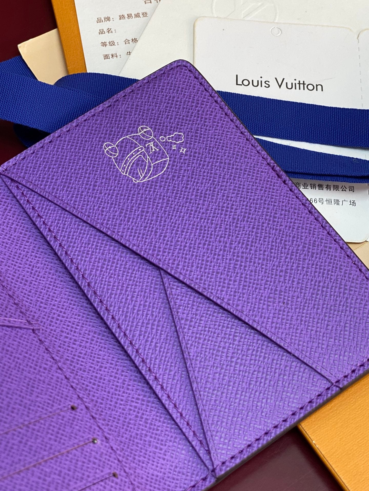Small bag card holder with signature-style line art logo on purple textured leather