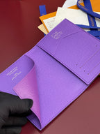 Purple small bag with Louis Vuitton 'Delie Homme 2026' text on folded flap