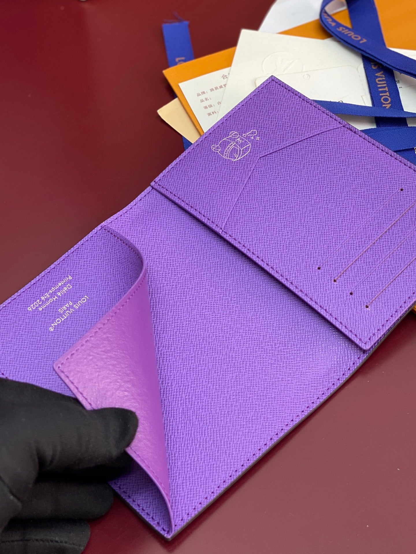 Purple small bag with Louis Vuitton 'Delie Homme 2026' text on folded flap