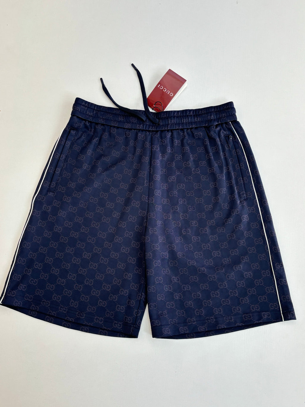 Navy patterned shorts with elastic waistband and drawstring cords, laid flat