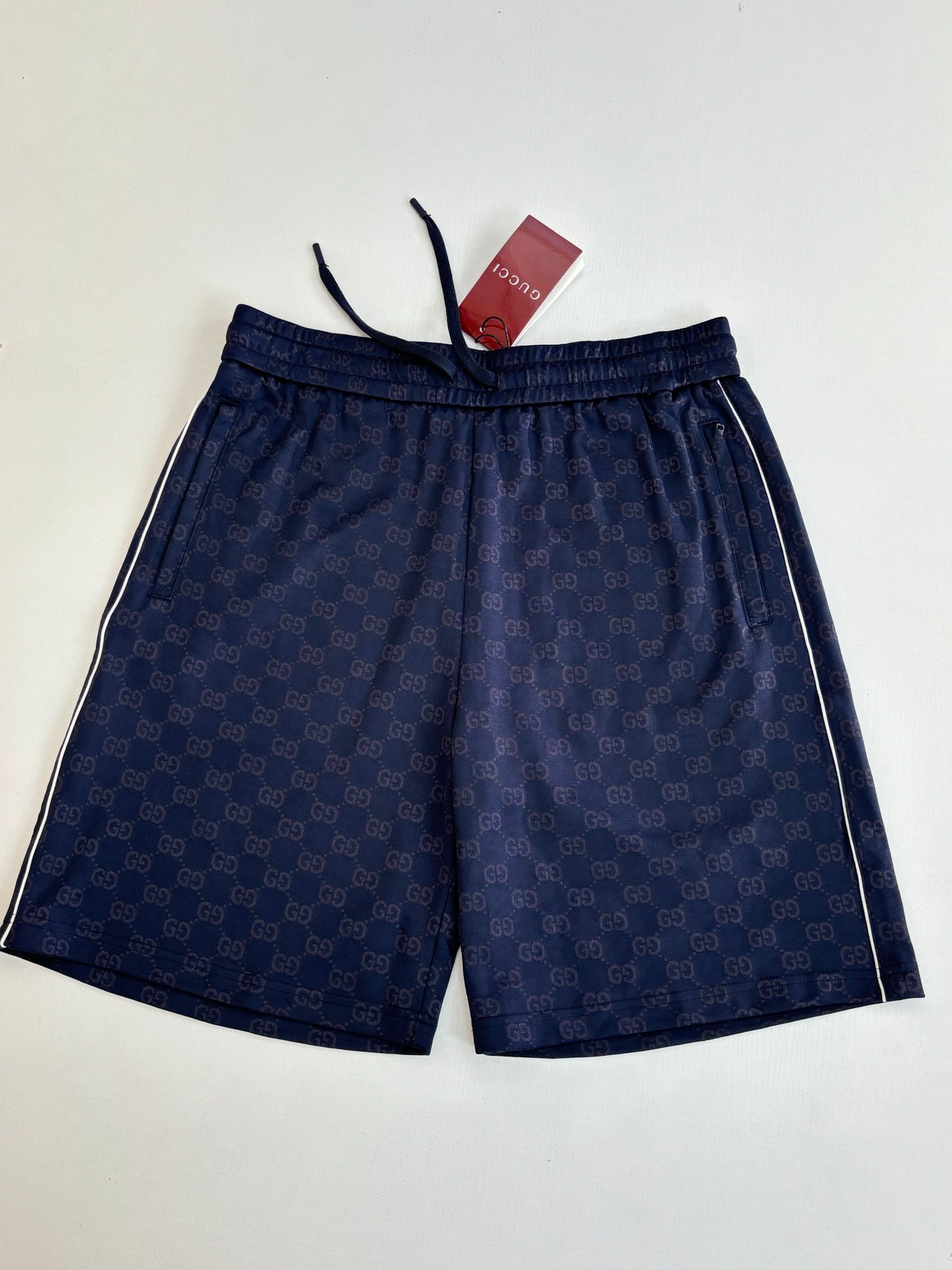 Navy patterned shorts with elastic waistband and drawstring cords, laid flat