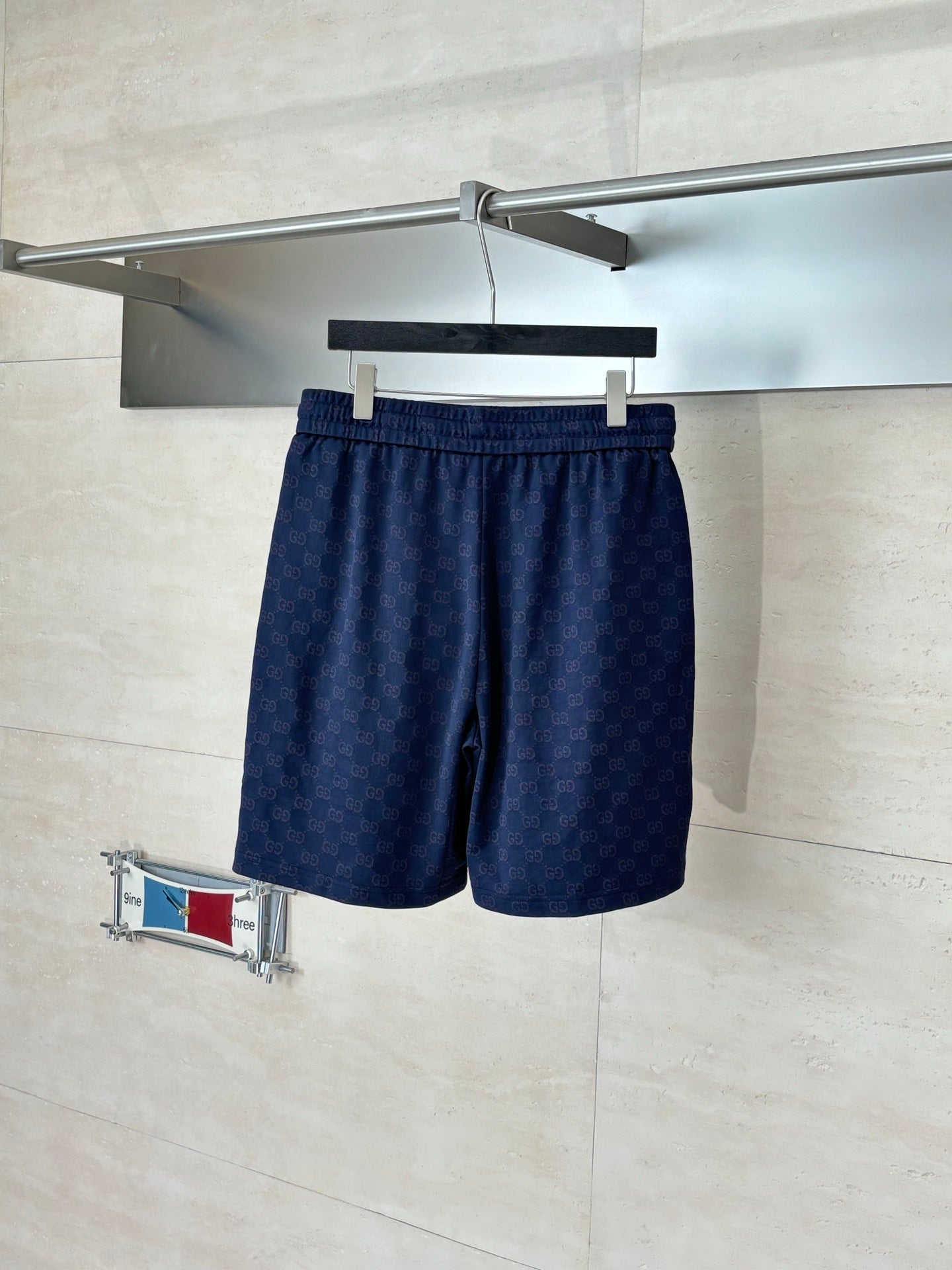 Navy patterned drawstring shorts with elastic waistband, side view on hanger