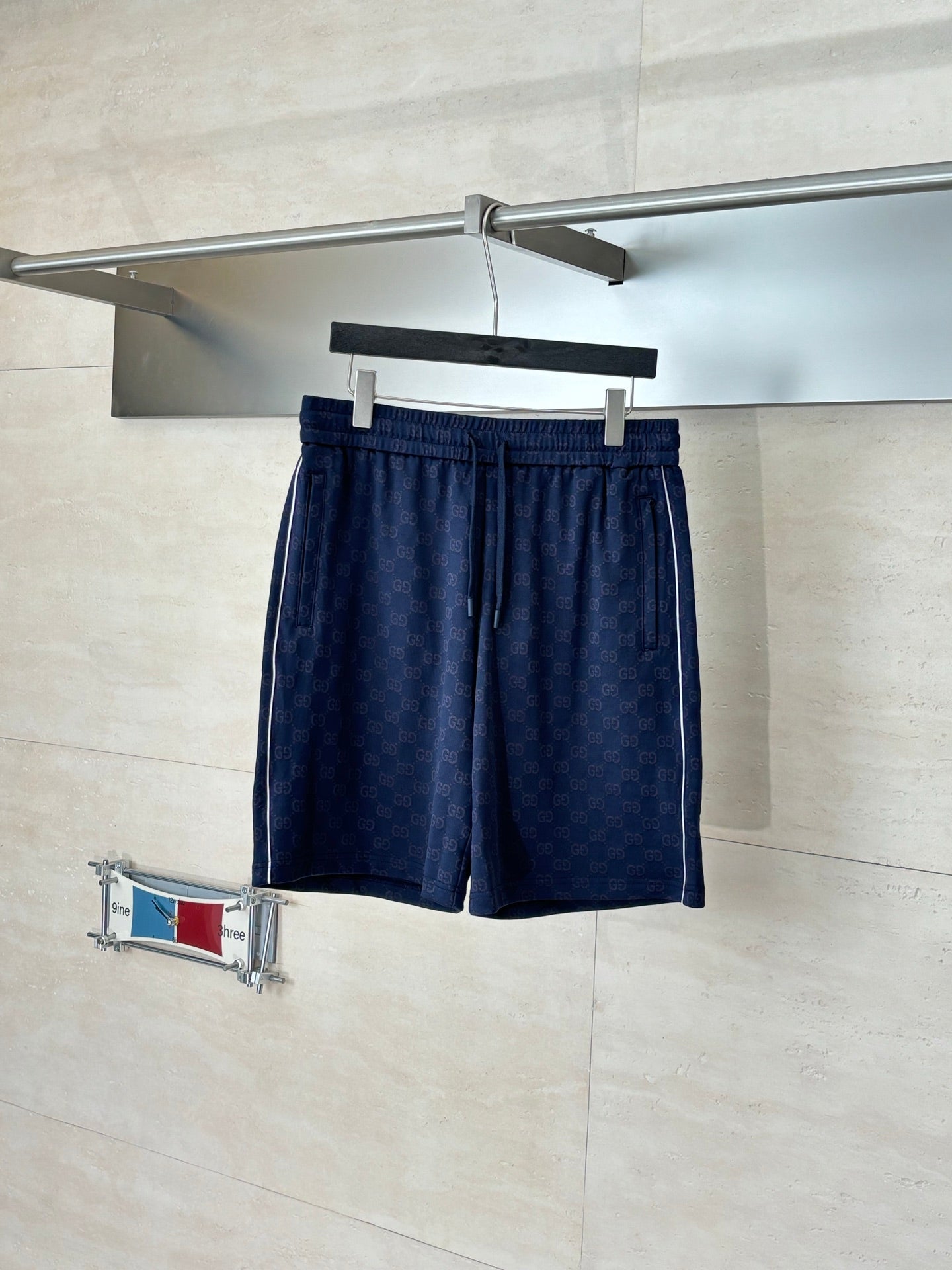 Navy patterned drawstring shorts with elastic waistband, hanging on a hanger