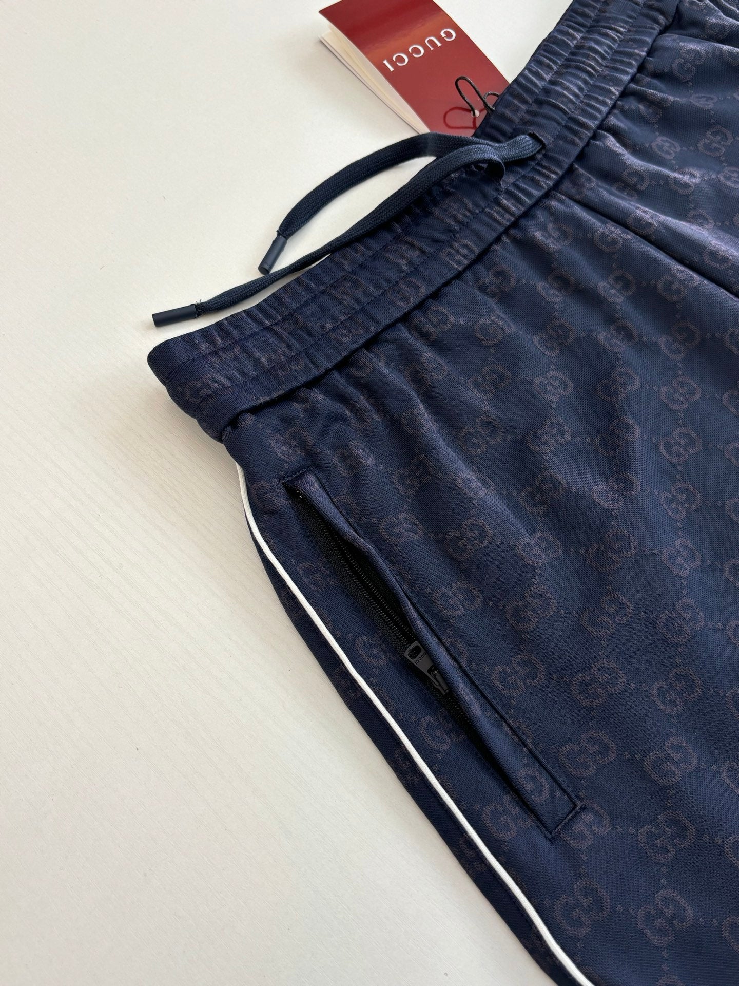 Navy drawstring shorts with textured elastic waist and allover pattern, close-up