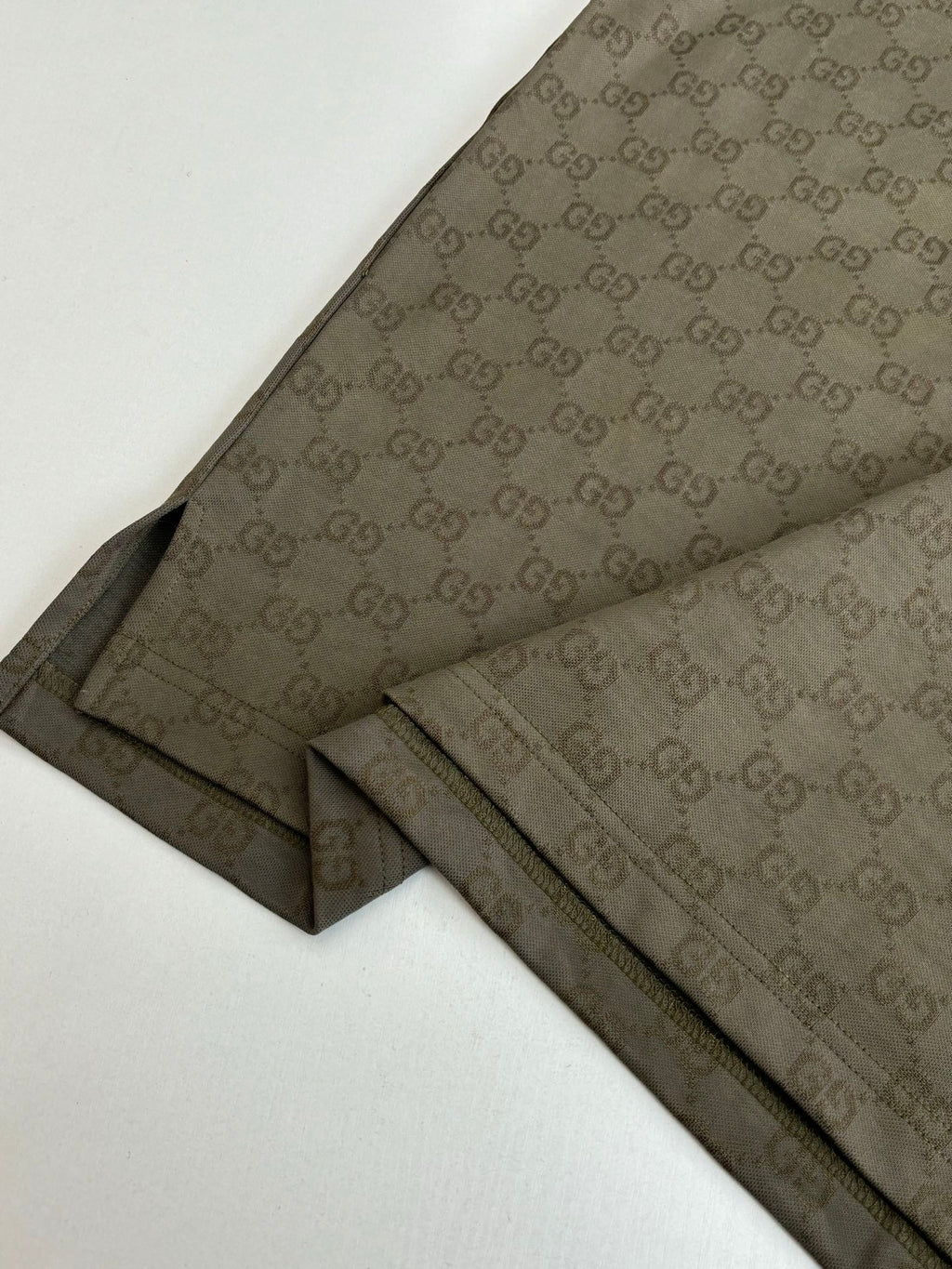 Gucci monogram shorts with dark olive side stripe and stitched hems, laid flat