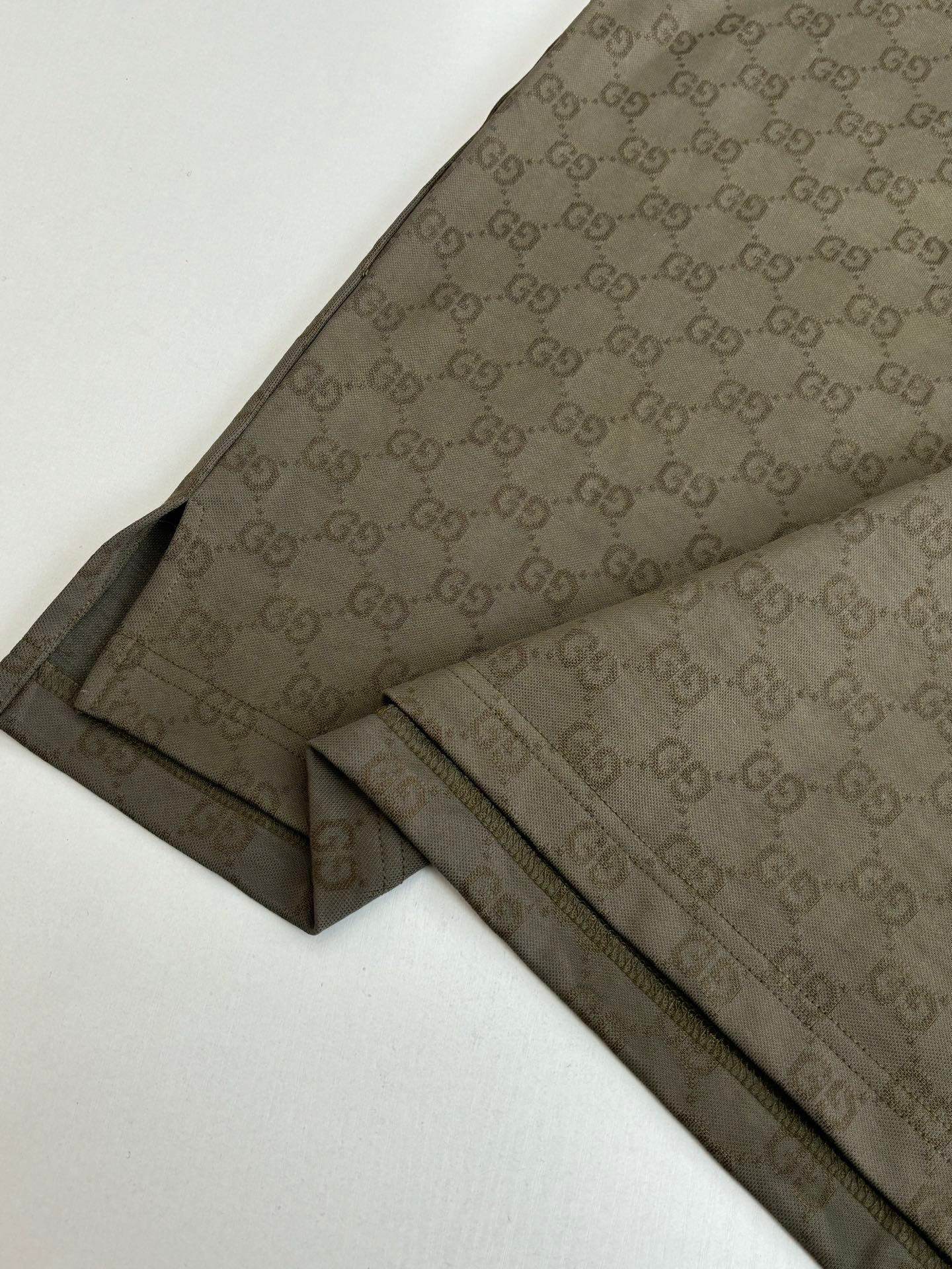 Gucci monogram shorts with dark olive side stripe and stitched hems, laid flat