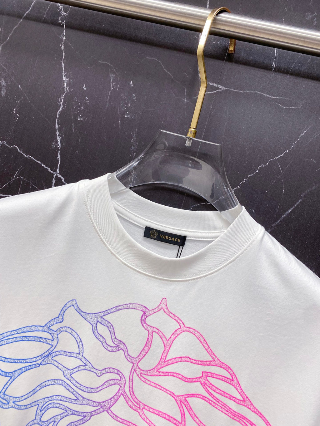 White T-shirt neckline with large blue and pink Medusa graphic, crew neck.